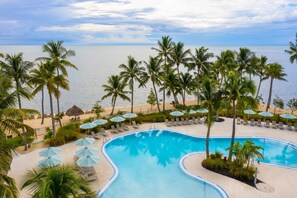 Una piscina al aire libre, sombrillas, sillones reclinables de piscina