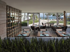 An outdoor dining area with wicker furniture and a view of the beach.