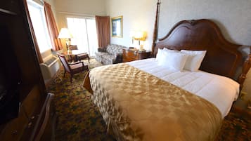 Ein Hotelzimmer mit einem großen Bett, einem Schreibtisch mit Lampe, einem Sessel und einem Kleiderschrank.