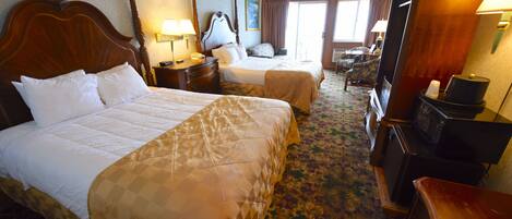 A hotel room with two beds, a desk, a chair, a television, and a window.