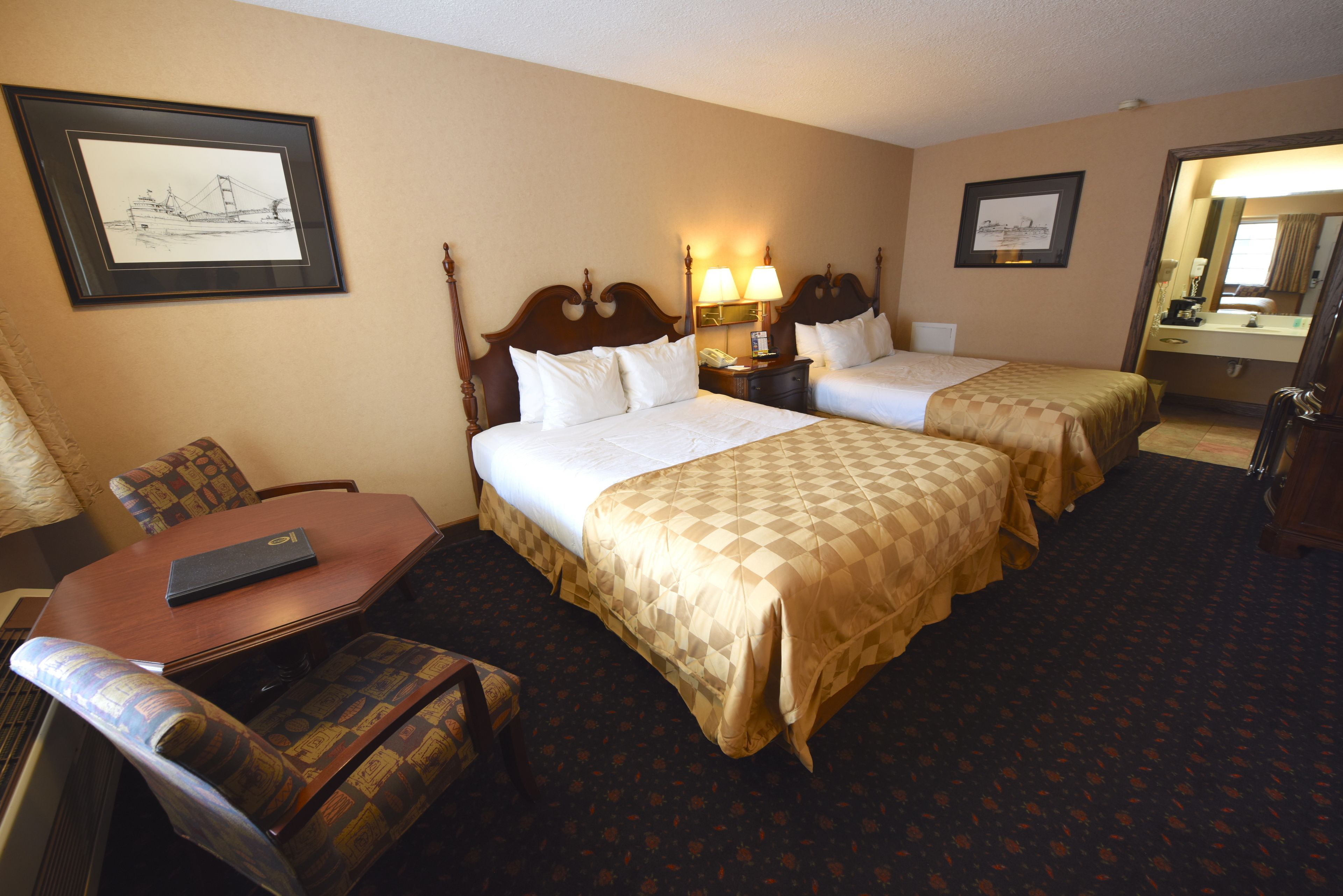 A hotel room with two beds, a desk, a chair, and a mirror.