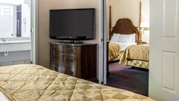 A hotel room with a large bed, a television on a dresser, and a separate bedroom with a bed and nightstand.