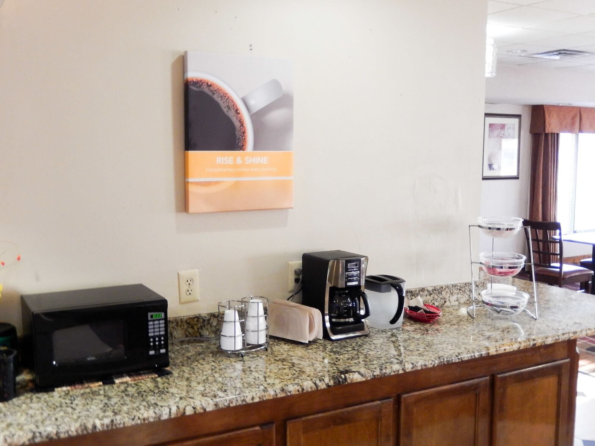 A kitchen area with a coffee maker, microwave, and a coffee cup on the counter.