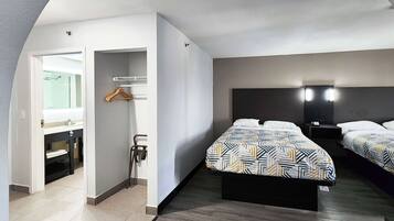 Ett hotellrum med en säng, sängbord, en spegel och ett badrum med en handduksställning.