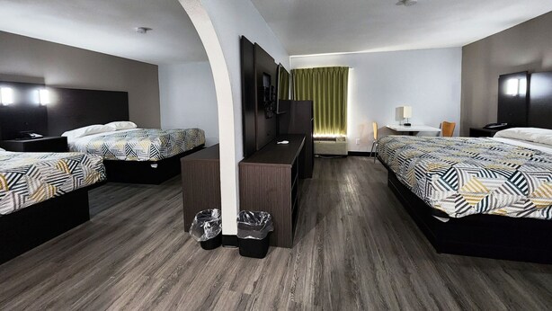 A hotel room with two beds, a desk, a chair, and a TV.