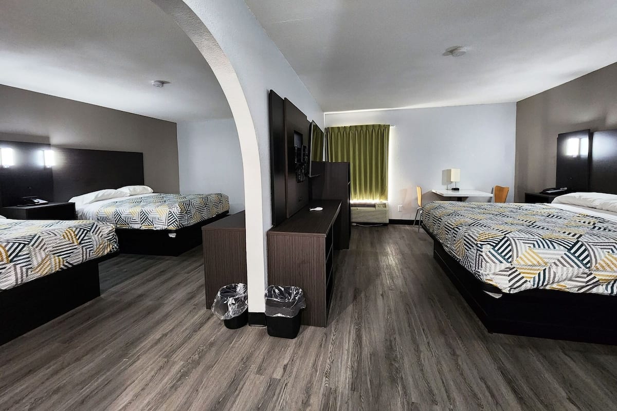 A hotel room with two beds, a desk, a chair, and a TV.