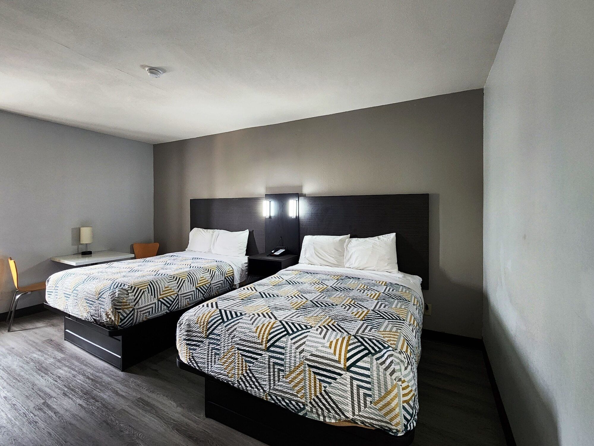 Une chambre d’hôtel avec deux lits, un bureau et une chaise.