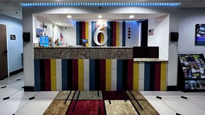 A reception area with a large number '6' sign, a counter with a computer, and a magazine rack.