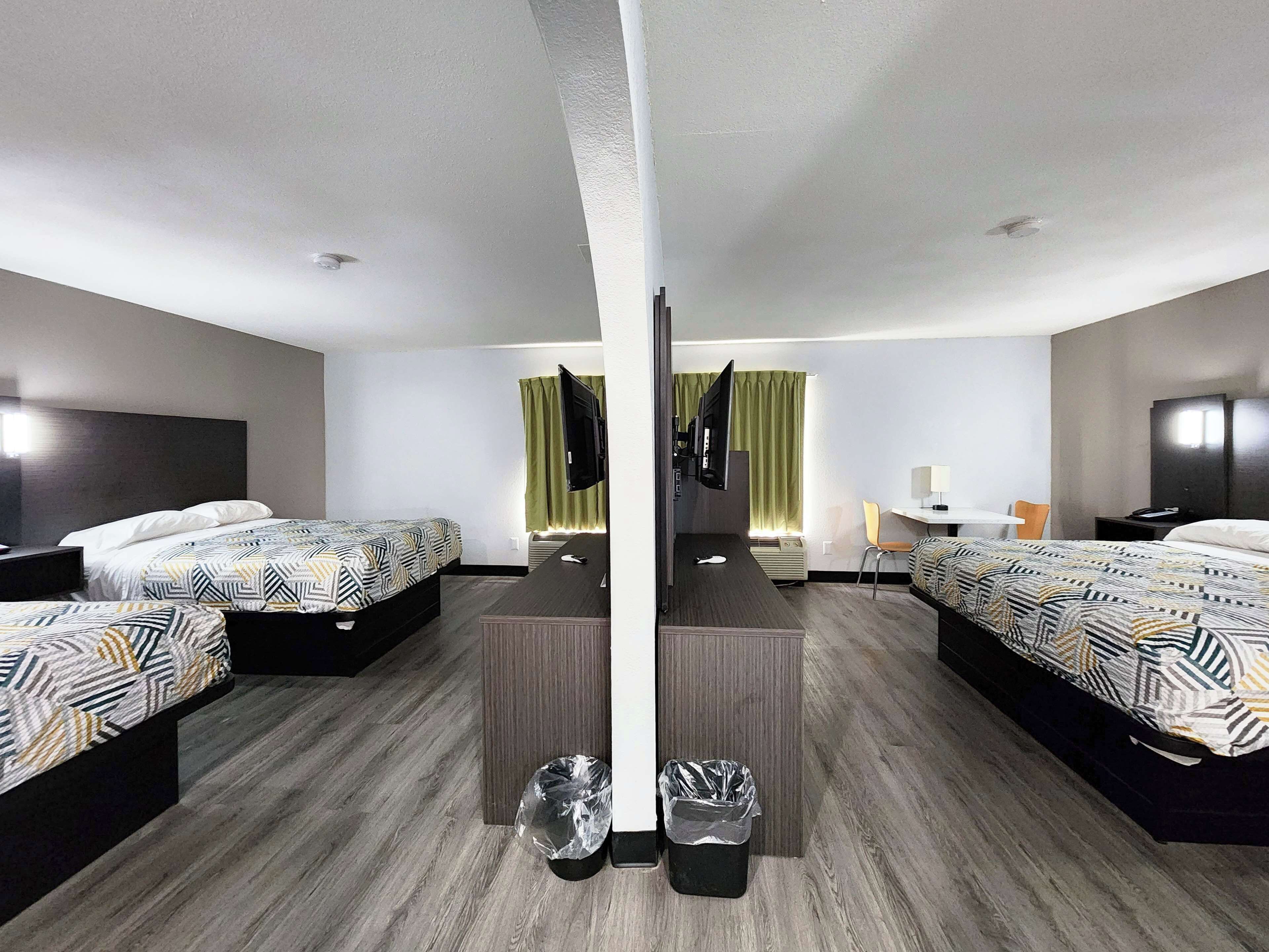 Habitación de hotel con dos camas, un escritorio, una silla, un televisor y un espejo.