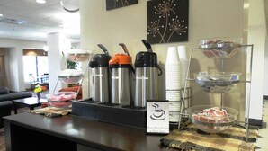 A buffet setup with stainless steel containers, a coffee station, and a sign indicating fresh coffee.