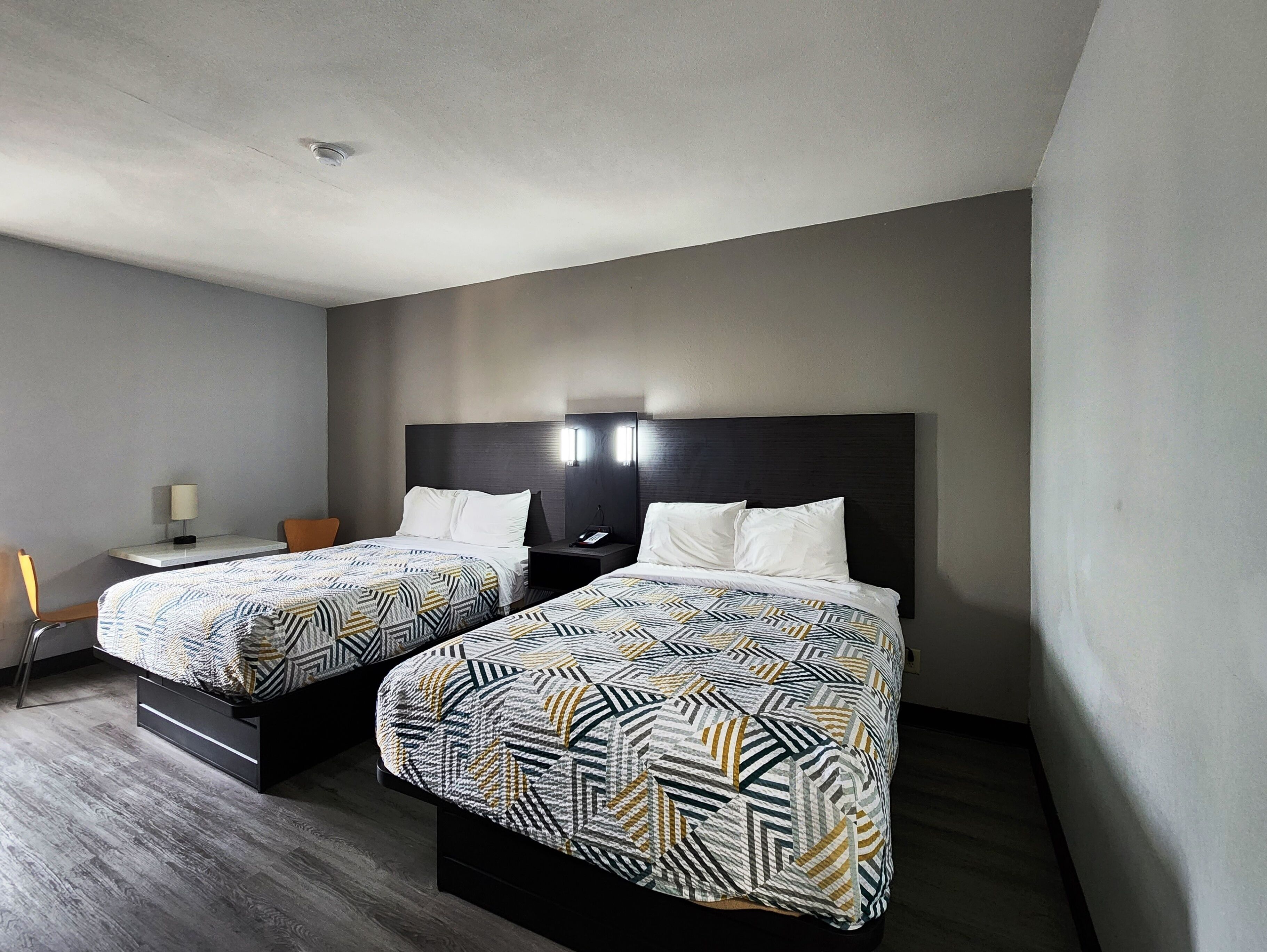 A hotel room with two beds, a desk, and a chair.