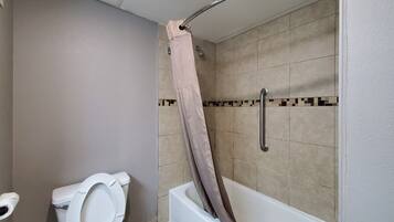 Un bagno con il water, una doccia dotata di maniglione e una vasca da bagno.