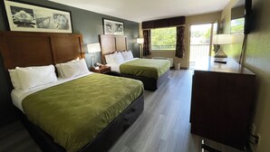 A hotel room with two beds, a TV, and a window with curtains.