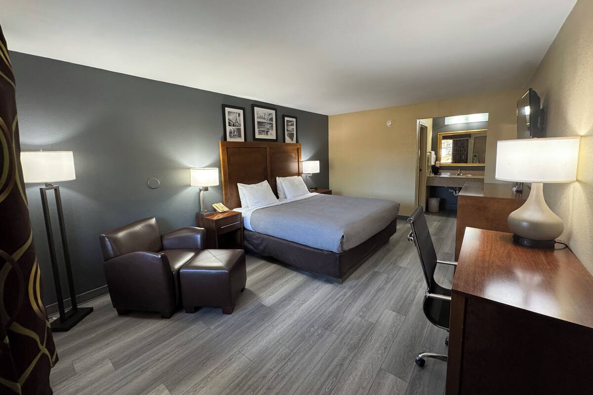 Ein Hotelzimmer mit Bett, zwei Stühlen, einem Schreibtisch und einem Spiegel.
