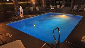 A swimming pool with lounge chairs and a lifeguard stand.