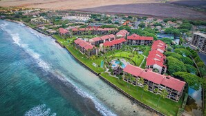 An aerial view of a coastal resort with multiple buildings, a beach, and a clear view of the ocean.