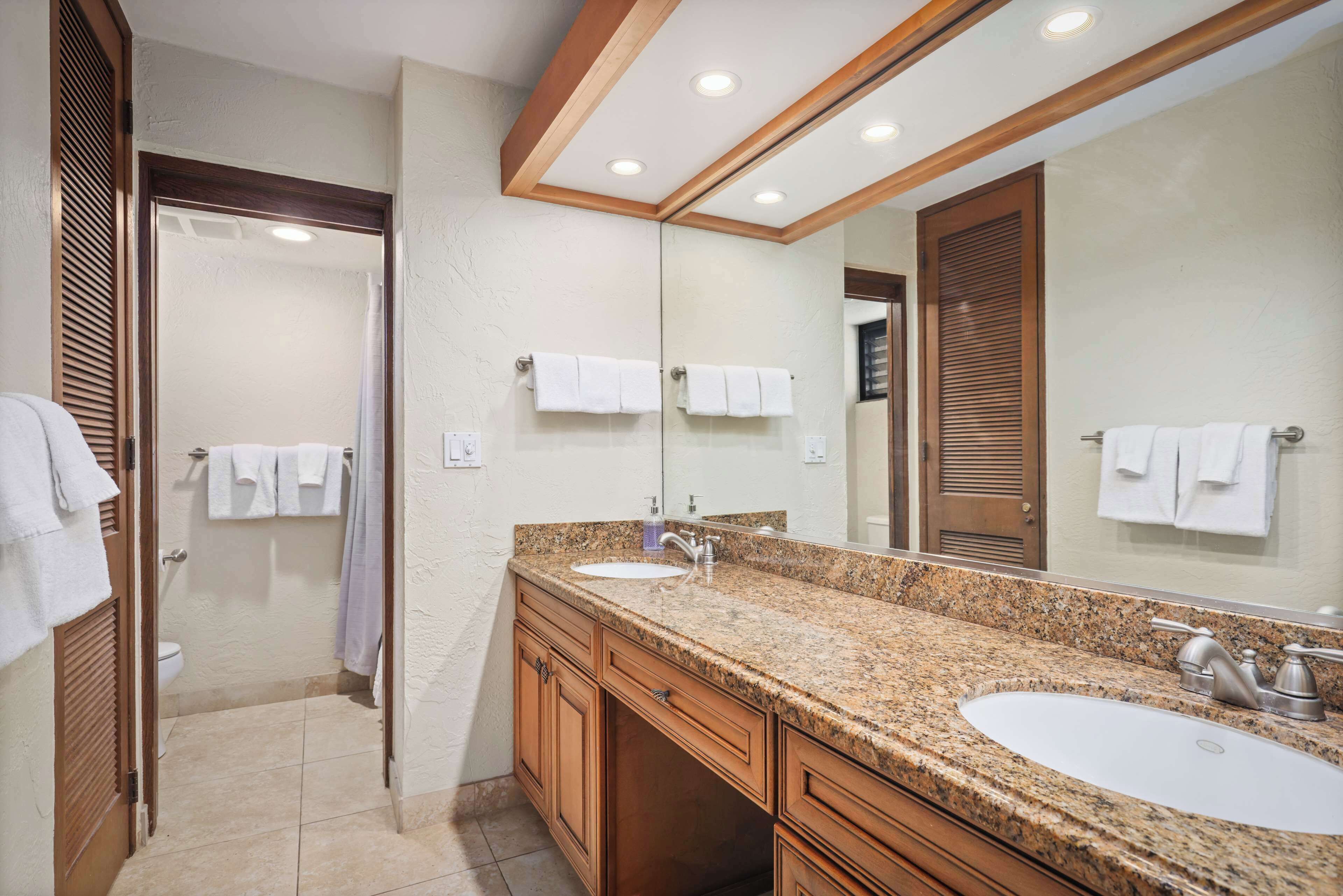 A bathroom with two sinks, a large mirror, and wooden cabinets.