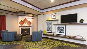 A modern living room with a fireplace, two sofas, a flat-screen TV, and framed pictures on the wall.