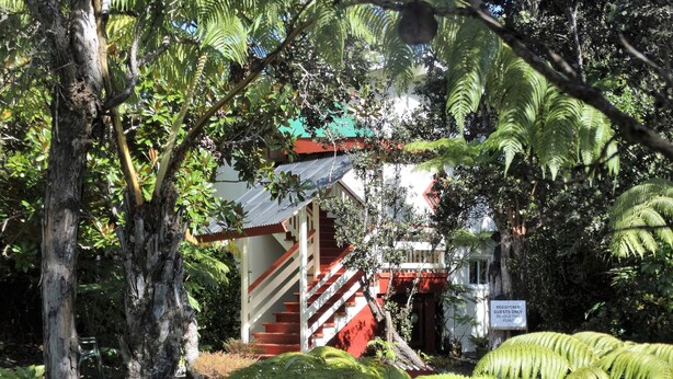 A building with a red staircase and a sign indicating it is a registered guest's only point. - Volcano Hale (Volcano)
