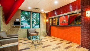 Un hall con una mesa de vidrio, zona de estar y una pared de ladrillo rojo con un letrero.
