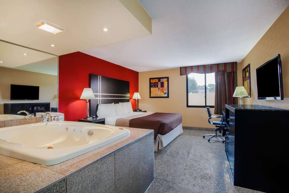 Une chambre d’hôtel avec une grande baignoire, un lit, un bureau et un téléviseur.