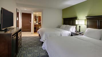 A hotel room with two beds, a TV, a desk, and a bathroom visible through an open door.
