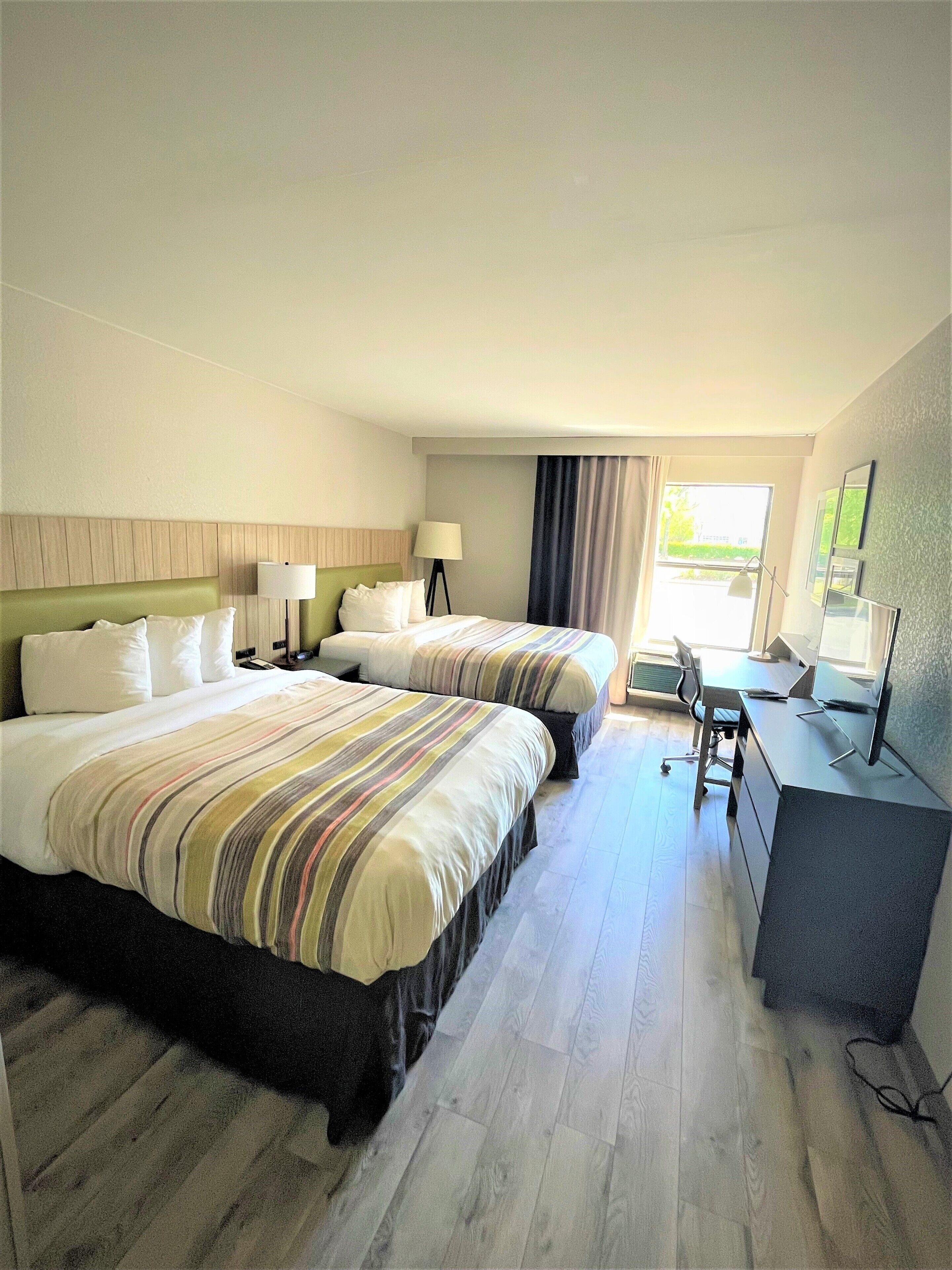 A hotel room with two beds, a desk, and a computer.