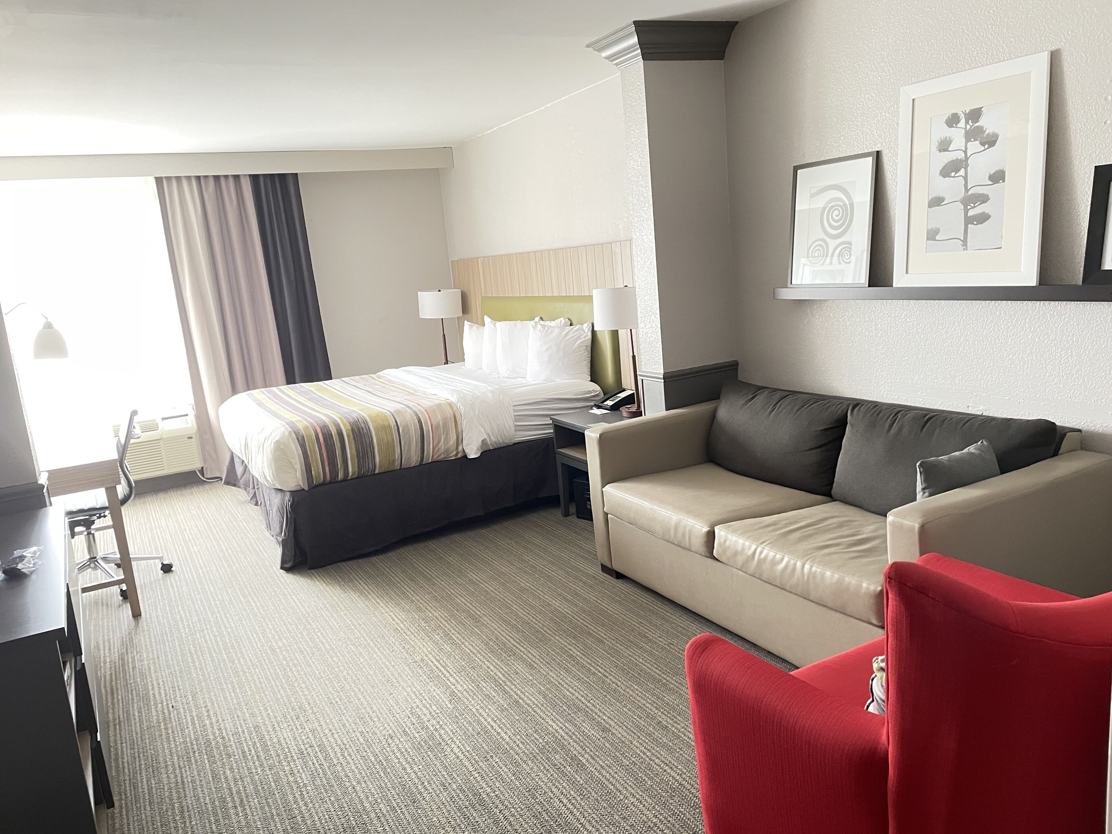 Une chambre d’hôtel avec un lit, un canapé, un bureau et une chaise.