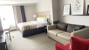 Une chambre d’hôtel avec un lit, un canapé, un bureau et une chaise.