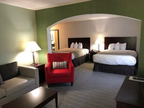Una habitación de hotel con dos camas, un sillón rojo, un sofá y un escritorio.