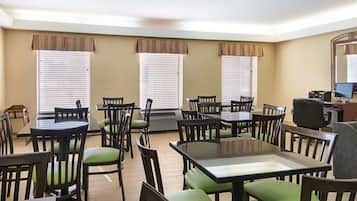 Habitació d'hotel amb zona de menjador que disposa de diverses taules i cadires, televisió i escriptori amb ordinador.