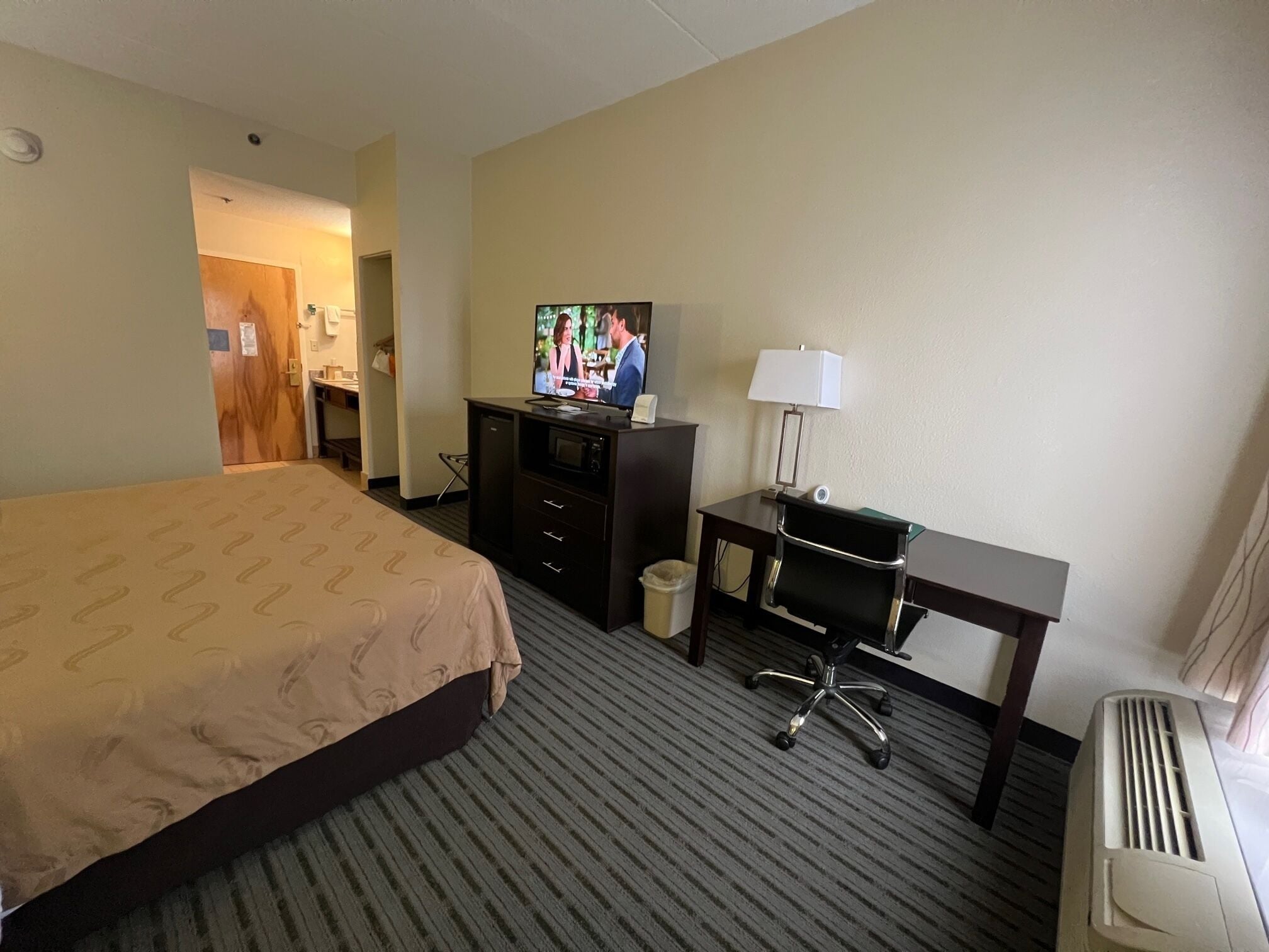 Une chambre d’hôtel équipée d’un lit, d’un bureau, d’une télévision, d’une lampe et d’une poubelle.
