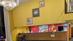 A hotel lobby with a reception desk, a chandelier, and a patterned carpet. - Super 8 by Wyndham Staunton (Staunton)