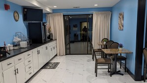 A modern kitchen with white cabinets, a black countertop, and a dining area with a table and chairs. - Super 8 by Wyndham Staunton (Staunton)