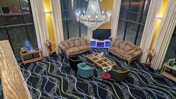 A modern living room with patterned carpet, two sofas, a coffee table, and a TV. - Super 8 by Wyndham Staunton (Staunton)