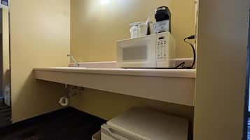 Een kitchenette met een magnetron, koffiezetapparaat en een kleine koelkast.
