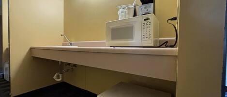 A kitchenette with a microwave, coffee maker, and a small refrigerator.