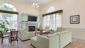 Un salon spacieux doté d’une cheminée, de sièges confortables et de grandes fenêtres.