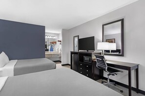 A hotel room with a bed, a desk with a chair, a TV, and a mirror.
