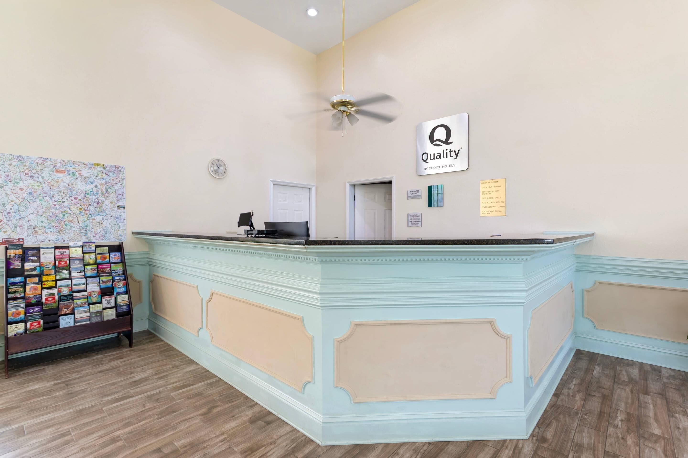 A reception desk with a 'Quality' sign, a clock, and a map display.