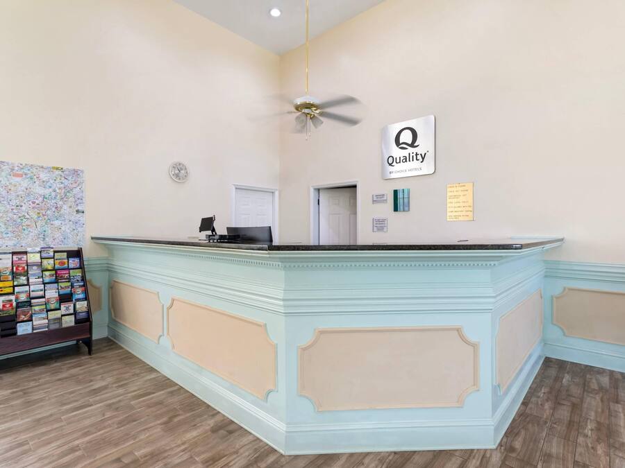 A reception desk with a 'Quality' sign, a clock, and a map display.