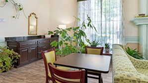 Un espace repas comprenant une table et des chaises, un canapé, une cheminée et des plantes en pot.