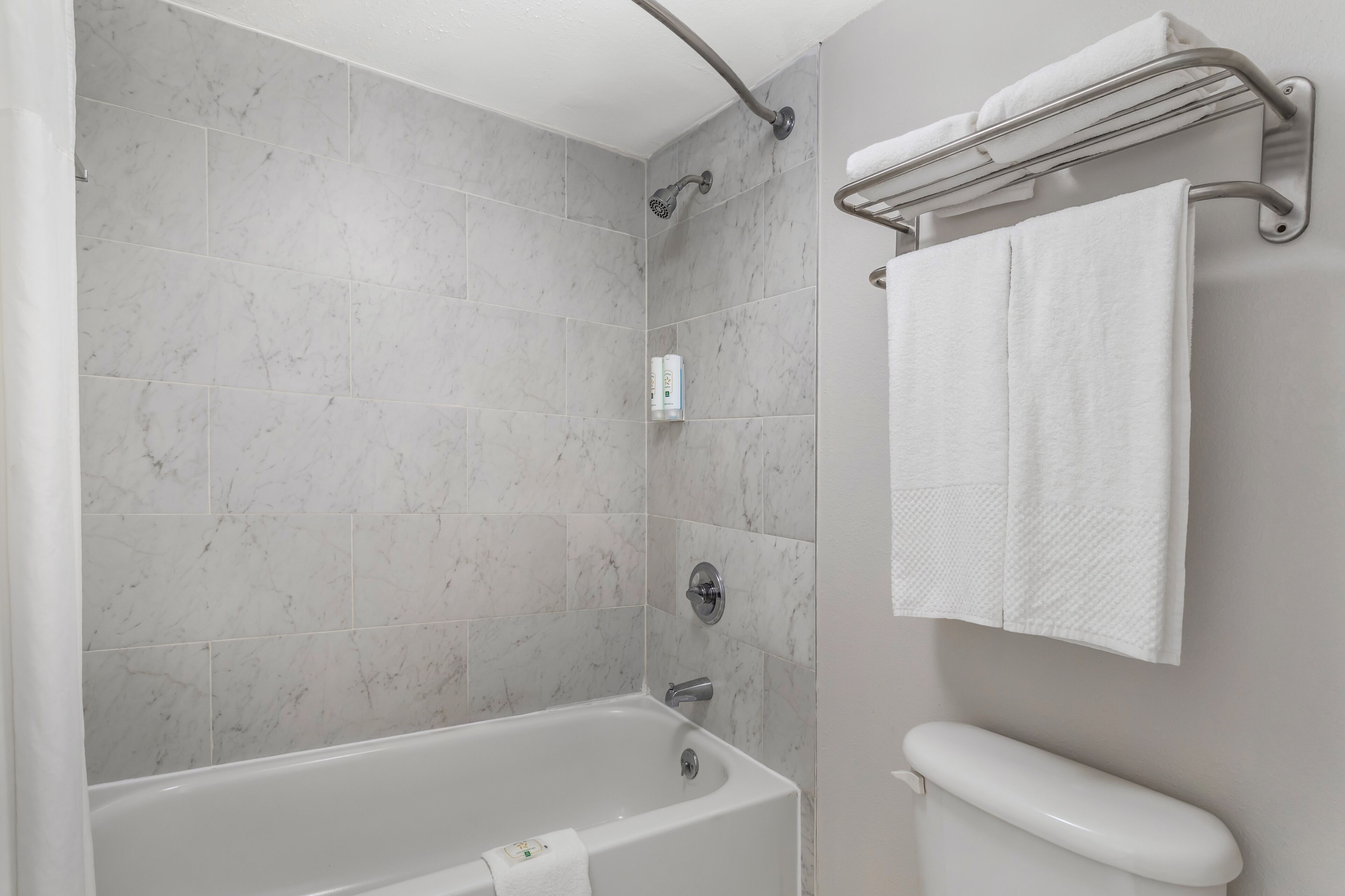 A bathroom with a bathtub, a shower, a toilet, and a towel rack.