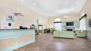 Un hall d’hôtel comprenant un comptoir d’accueil, une cheminée, un espace salon et un ventilateur de plafond.