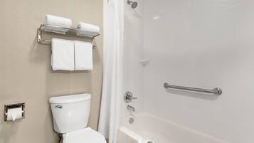 Un baño con inodoro, bañera con cortina de ducha y toallero con toallas.