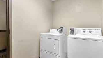 A laundry room with two white front-loading washing machines and a dryer.