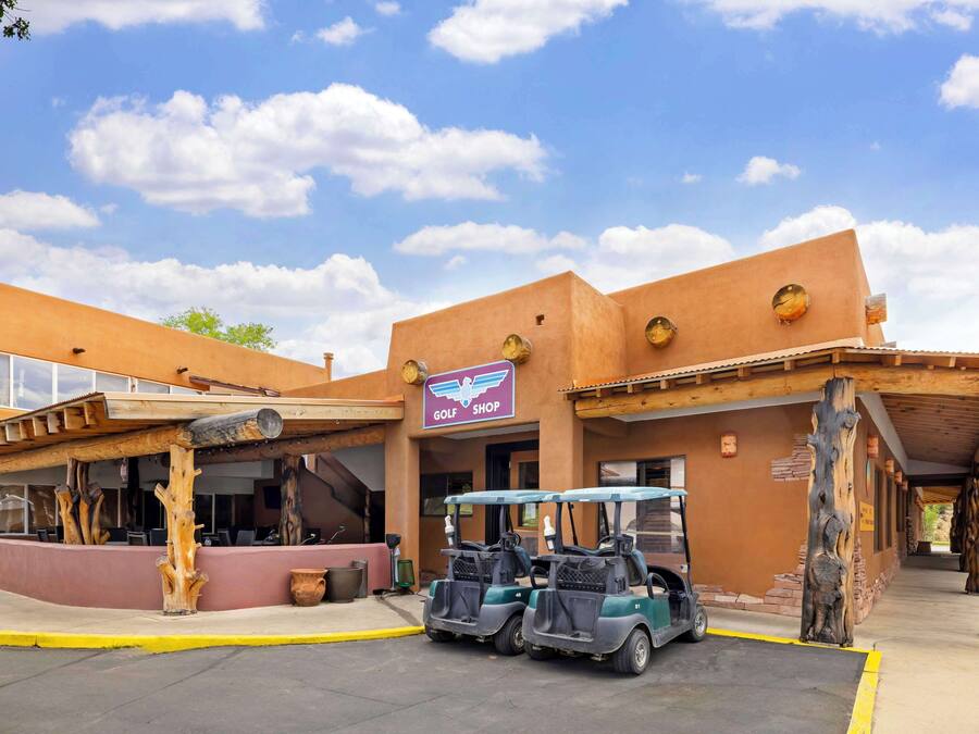A building with a 'GOLF SHOP' sign, two golf carts, and a covered area with wooden beams.