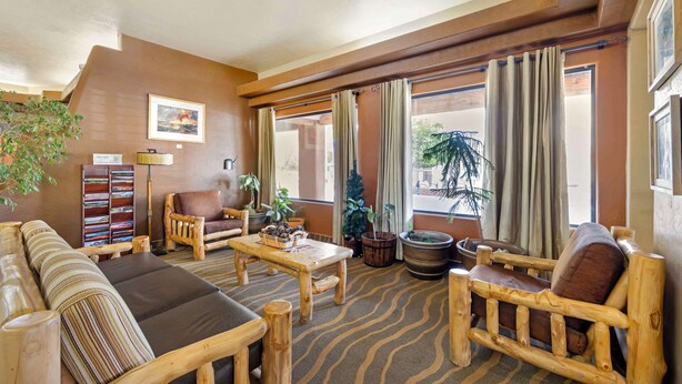 Een gezellige kamer met een bank, houten stoelen, een tafel en een boekenplank.