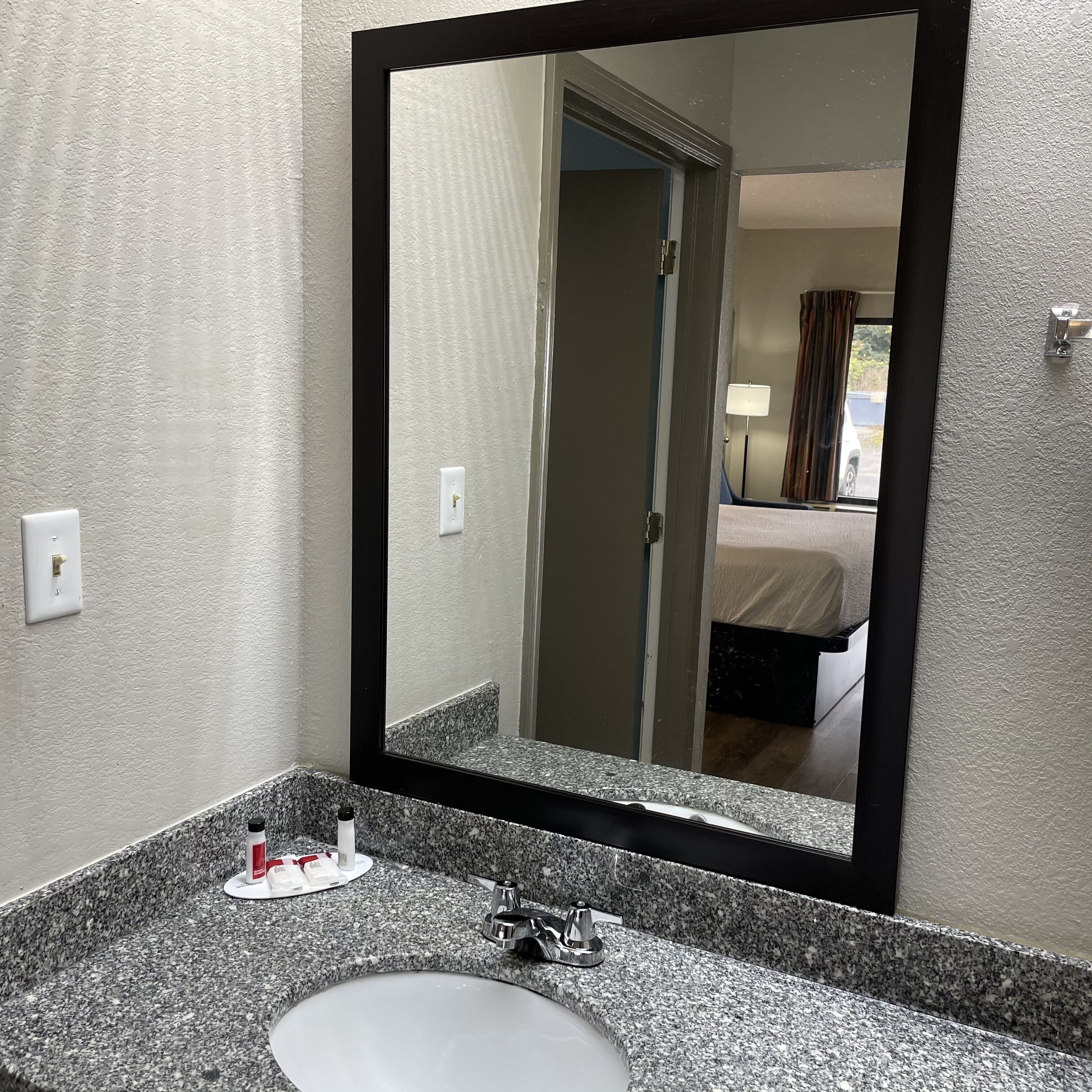 A bathroom with a granite countertop, a sink, and a mirror.