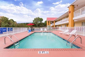 A swimming pool with a 5 ft depth limit, a red umbrella, and a white fence. - Days Inn by Wyndham Trenton (Trenton)